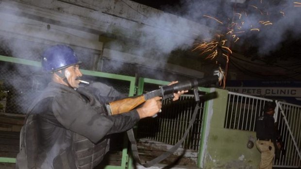 A policeman fires tear gas to disperse supporters of Muhammad Tahirul Qadri, Sufi cleric and leader of political party Pakistan Awami Tehreek (PAT), during a protest in Lahore August 8, 2014.