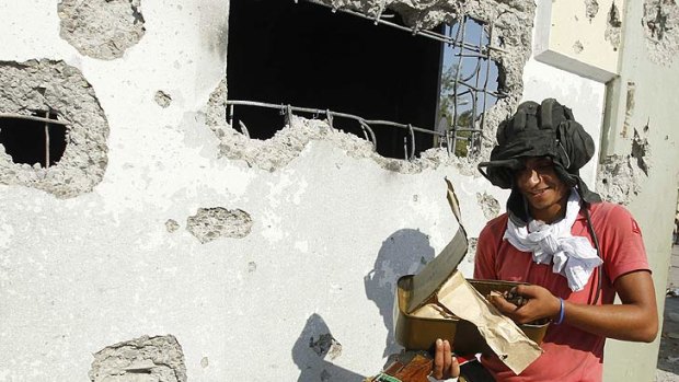 A Libyan rebel fighter collects ammunition from the Gaddafi compound.