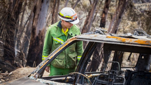 A firefighter inspects a burnt-out car in Wye River.