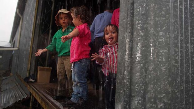 Silver lining: Campbell Ritchie, 5, with sisters Alexandra, 3, and Georgina, 1, enjoying the downpour.