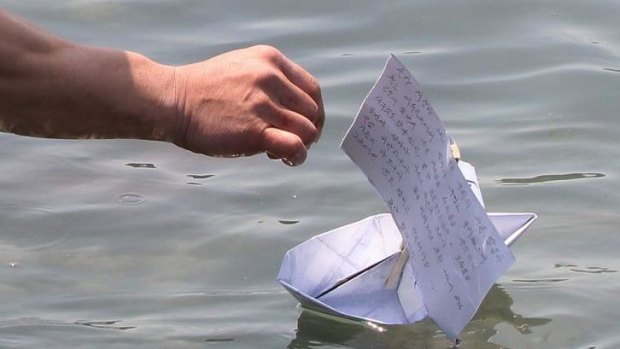 A passenger's relative releases a paper boat with the message for a safe return at Jindo.