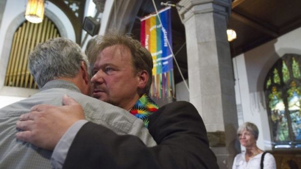 Reverend Schaefer hugs a supporter after his reinstatement in June.