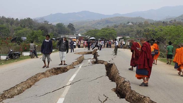 Impassable ... Buddhist monks join residents inspecting the damage on the main road into Tarla.
