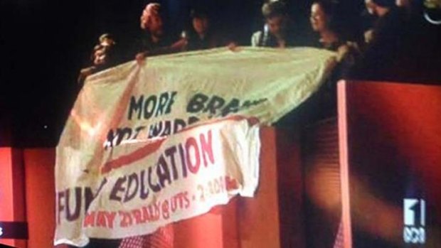 Students wave a banner as part of a protest on ABC's <i>Q&A show</i> on Monday night.
