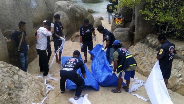 Thai police officers with the bodies of two British tourists found murdered on a Koh Tao beach.