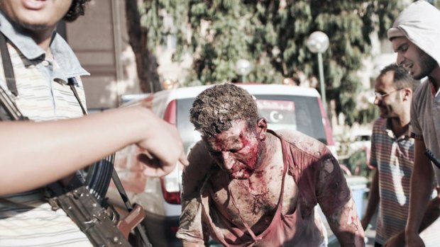 A wounded Gaddafi-loyalist is walked to a rebel-held hospital in central Tripoli by his captors.