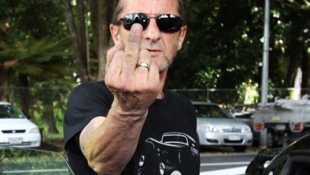 Former AC/DC drummer Phil Rudd gestures to members of the media after leaving Tauranga District Court in 2014.