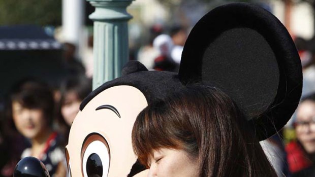 Comfort ... a Japanese woman gets a hug from Mickey Mouse at Tokyo Disneyland in Urayasu, which reopened yesterday.