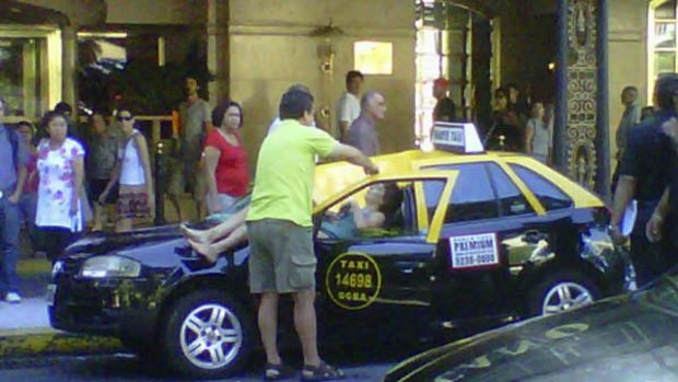 In this photograph taken with a mobile phone, a woman lies injured atop a taxi where she fell from the 23rd floor of the Hotel Panamericano in Buenos Aires.