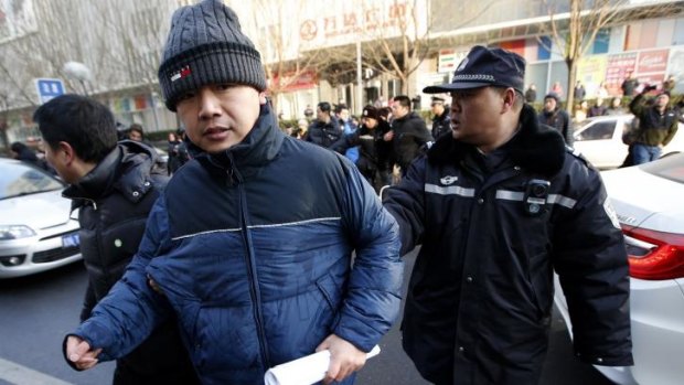 Policemen escort Zhang Qingfang, the lawyer of Xu Zhiyong, away from journalists after Xu's trial.