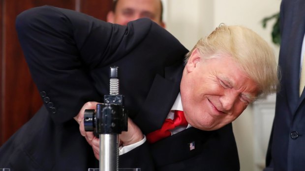 US President Donald Trump tries unsuccessfully to crush a Corning glass sample during an event in the White House on Thursday. 