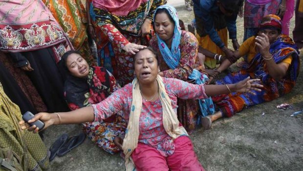 Relatives of victims mourn outside the remains of the collapsed factory building.