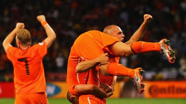 John Heitinga of the Netherlands carries Wesley Sneijder as they celebrate victory over Uruguay.