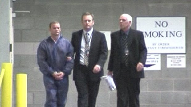 Kaine McNamara (left) is escorted by officers after being charged at Curtin House.