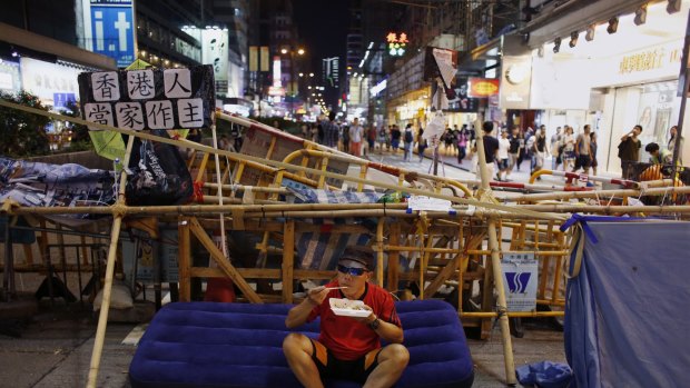 A pro-democracy protester eats his meal in front of a barricade blocking a main road in Hong Kong's Mongkok shopping district on Wednesday night.