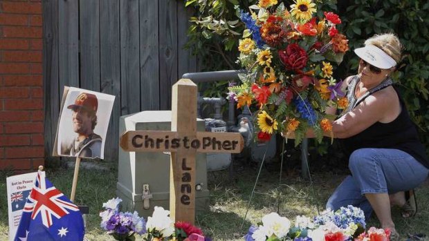 An Oklahoma resident places flowers at a memorial at the scene where Australian college student Christopher Lane was killed.