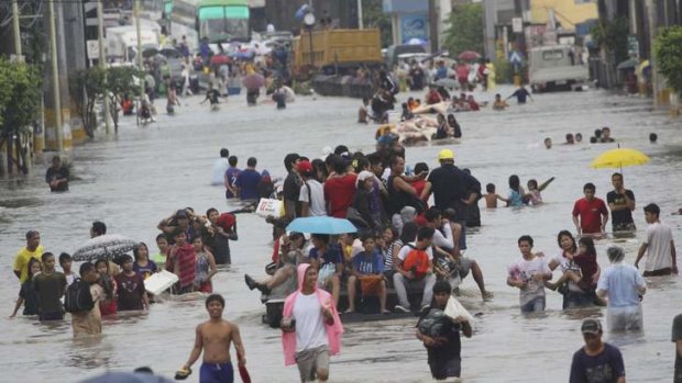 People wade through floodwaters brought by monsoon rain and intensified by tropical storm Trami, in Las Pinas city, south of Manila.
