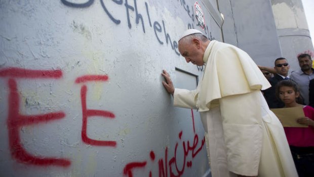 Reaching out: Pope Francis prays at the separation barrier.