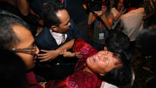 A Chinese relative of a passenger aboard the missing MH370 is carried out of a press conference by security officials.