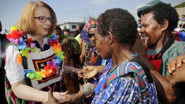 Happy days: Prime Minister Julia Gillard gets a colourful welcome as she mixes with local people at a market in Port Moresby.