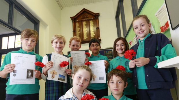 Grade 3 and 4 students at the Flemington Primary School with the ANZAC  honour board, which they received a grant to restore.