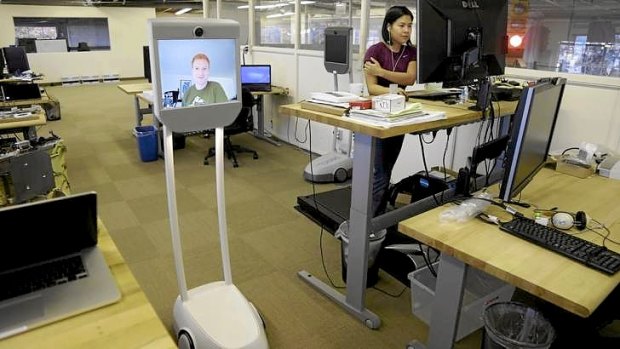 Senior software engineer, Josh Faust, seen on screen, navigates his company's office using a Beam remote presence system, as fellow engineer Stephanie Lee, at right, works on a project at Suitable Technologies in Palo Alto, California.