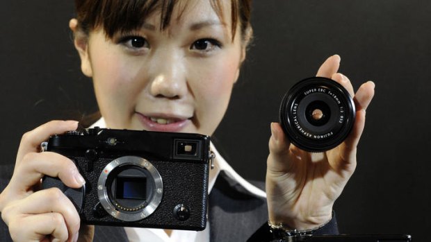 An employee of Japanese camera manufacturer Fujifilm displays the company's new interchangeable lens digital camera "X-Pro1", equipped with a 16.3 mega-pixel APS-C sized CMOS image sensor.