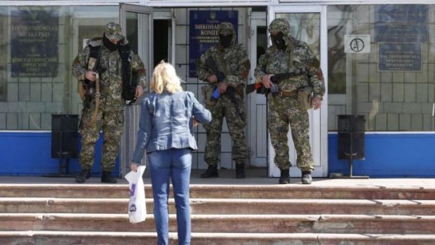 A woman observes pro-Russian armed men guarding a seized city council building in Kostyantynivka.