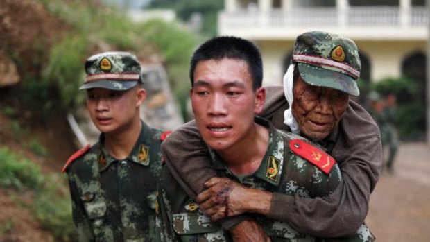 A paramilitary policeman carries an elderly man after the earthquake.