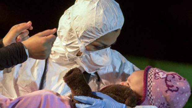 A rescuer cradles a child in the Sicilian harbor of Pozzallo, Italy, early on Monday. About 100 migrants, including 28 children, were rescued on Sunday by a merchant vessel in the Sicilian Strait while they were trying to cross. 