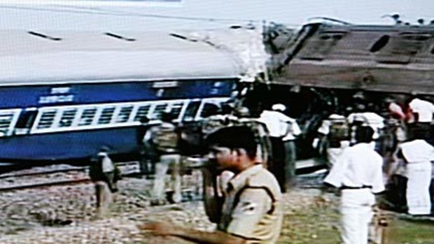 Rescue workers stand beside the wreckage of the train that crashed in India.