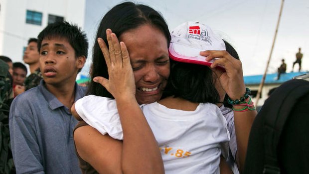 A woman carrying a child cries as other survivors of Typhoon Haiyan wait to board a C130 aircraft during the evacuation of hundreds of survivors of Typhoon Haiyan in Tacloban, Philippines.