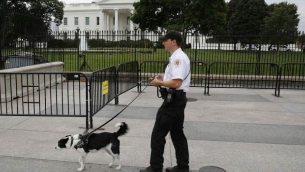 A US Secret Service Uniformed Division officer and his bomb-sniffing dog walk along the north fence of the White House along Pennsylvania Avenue in Washington.