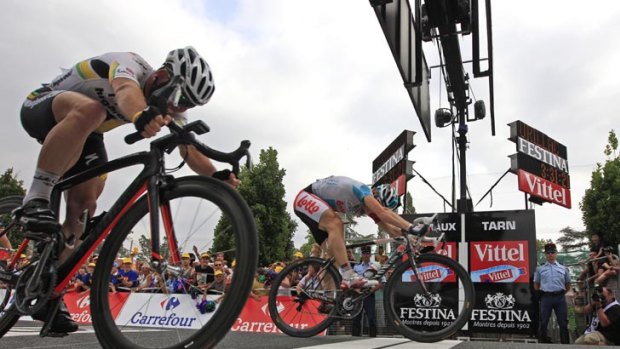 Andre Greipel of Germany, rear, pushes his wheel over the finish line ahead of second place Mark Cavendish of Britain, left, to win the 10th stage of the Tour de France.