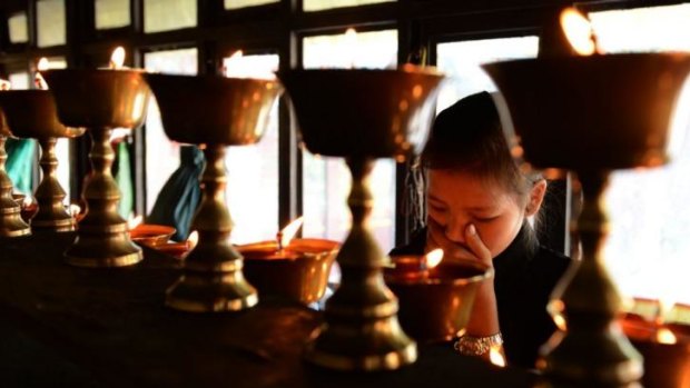 A daughter lights a candle for her father who died in the avalanche at the Sherpa Monastery in Kathmandu.