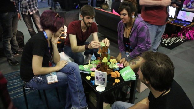 Visitors of the IndieCade booth play a tabletop game called Grow, where players accrue points by building a tree
