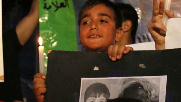 Remembered ... a Syrian child carries pictures of 13-year-old Hamza al-Khatib as another boy holds a candle during a protest in front of the United Nations building in Beirut, Lebanon.