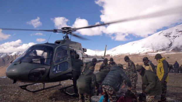 An injured survivor of the snowstorm is assisted by army personnel into a Nepalese Army helicopter in Manang District on the Annapurna Circuit hiking trail.