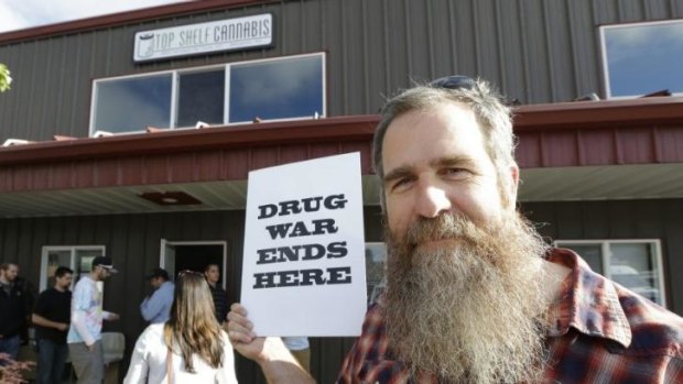 Kevin Nelson holds a sign outside Top Shelf Cannabis in Bellingham, Washington.