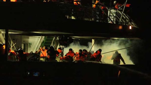 Passengers on the second deck of the Mavi Marmara run as they are surrounded by smoke from the tear gas .