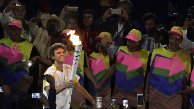 Former Brazilian tennis player Gustavo Kuerten arrives with the Olympic flame.