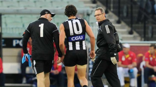 Scott Pendlebury in the hands of club doctors during the game against Gold Coast.