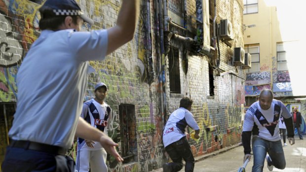 Police and Indian students play a game of laneway cricket in the CBD yesterday.