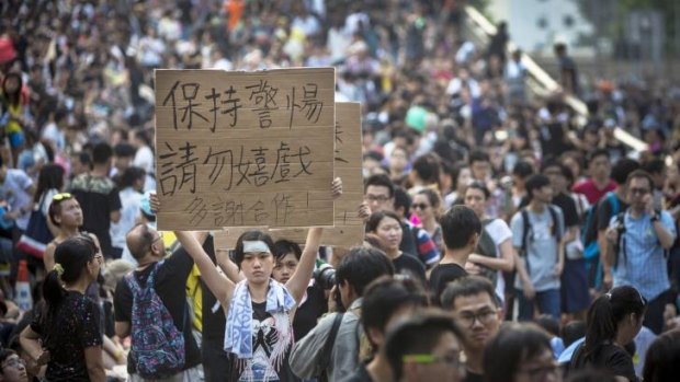 A pro-democracy demonstrator holds up a sign as thousands pack the streets at a protest site in Hong Kong.