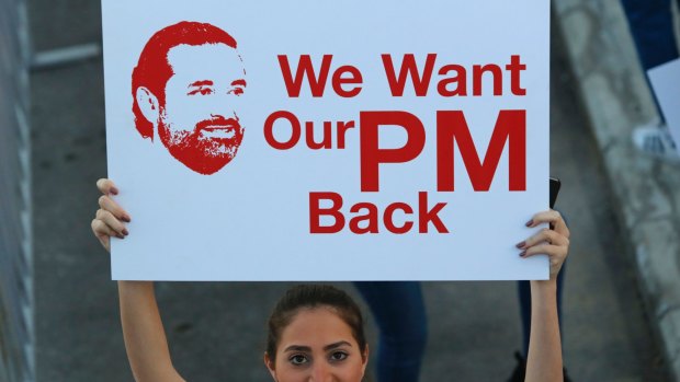 A Lebanese woman holds a placard supporting the outgoing Lebanese Prime Minister Saad Hariri to return from Saudi Arabia during the Beirut Marathon, in Beirut, Lebanon, on Sunday.