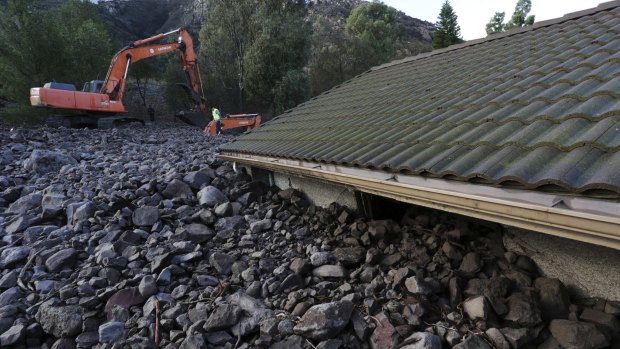 Covered up: Rocks reach the roof of a home after a mudslide struck at least eight homes during heavy rains in Camarillo Springs, California.