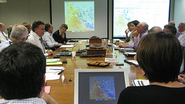 Premier Anna Bligh (front right, with her back to the camera) in an emergency briefing this morning.