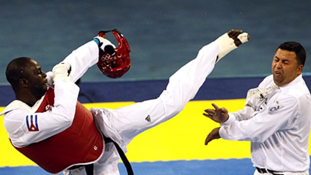 Angel Valodia Matos of Cuba kicks a referee during his bronze medal taekwondo bout.