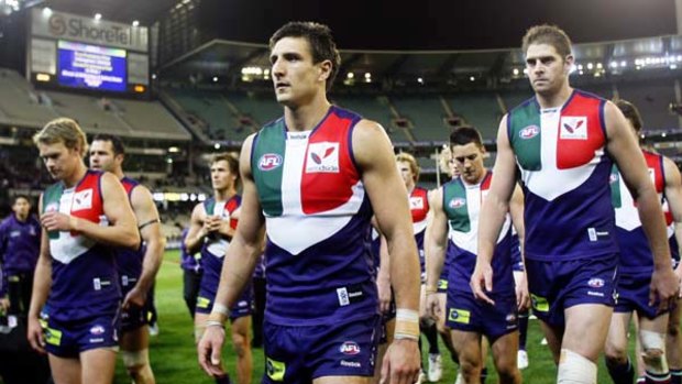 A dejected Dockers captain, Matthew Pavlich, leads his teammates off the ground after they were thrashed by the Cats.