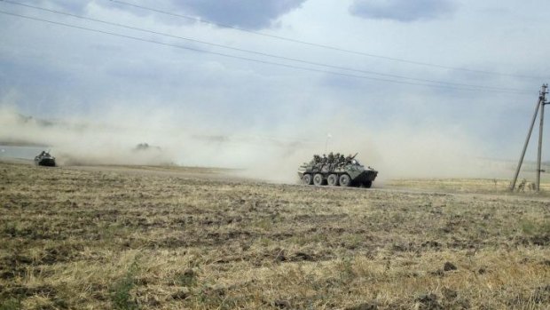 Armoured vehicles, suspected of carrying Russian troops, drive across the Ukrainian countryside near the village of Krasnodarovka.